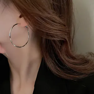 Close-up of a minimalist silver oval hoop earring worn by a model for an elegant look.