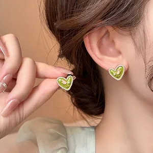Primo piano di orecchini a cuore in smalto verde con perle e dettaglio tulipano