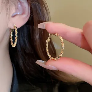 Macro view of golden oval hoop earrings featuring a unique geometric textured surface design
