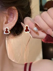 Detailed macro view of red enamel gourd-shaped stud earrings with sparkling zircon pavé border