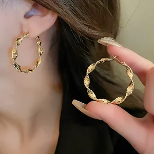 Detailed view of elegant gold twisted hoop earrings worn by a model for a chic look