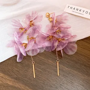 Détail de boucles d'oreilles fleurs en tulle mauve avec élégants glands dorés et tiges argent.