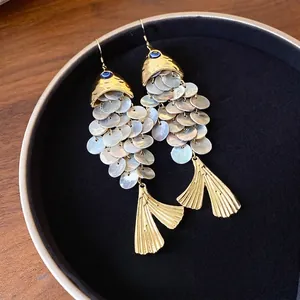 Orecchini a forma di pesce dorati con scaglie di conchiglia e dettaglio occhio greco