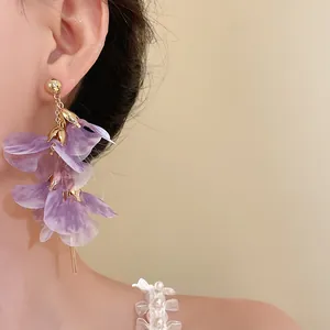 Détail en gros plan d'élégantes boucles d'oreilles à fleurs en résille violette