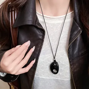 Vue rapprochée d'un collier pendentif ovale en résine noire minimaliste sur un mannequin