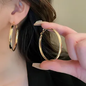 Close-up of minimalist gold oval hoop earrings with shiny metallic finish