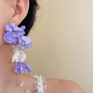 Détail des boucles d'oreilles à fleurs en résille avec pétales violet et blanc