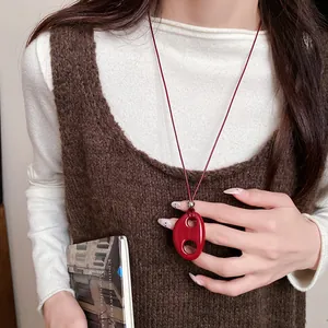 Détail du collier pendentif ovale creux en résine rouge au style rétro minimaliste