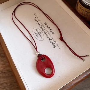 Vue détaillée d'un collier pendentif ovale en résine rouge sur un cordon minimaliste