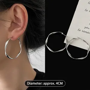 Detail view of twisted silver hoop earrings showing a diameter of approximately 4cm