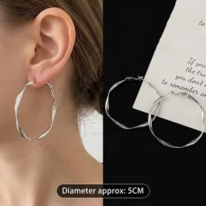 Detailed view of large 5cm twisted silver hoop earrings with a sleek minimalist design.