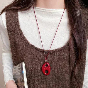 Collier avec pendentif ovale évidé en résine rouge porté dans un style vintage