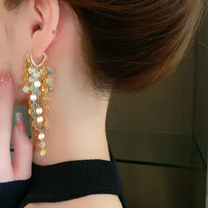 Zoom sur les boucles d'oreilles à pampilles dorées avec manchette en cœur et paillettes