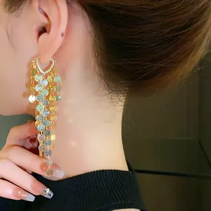 Gros plan détaillé d'élégantes boucles d'oreilles à pompons en paillettes dorées sur un modèle