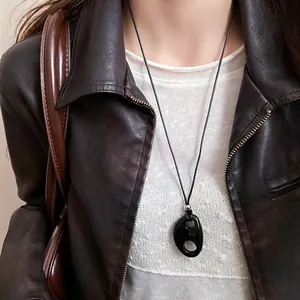Gros plan d'un collier pendentif ovale évidé en résine noire style rétro