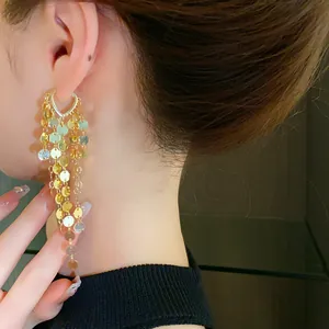 Gros plan détaillé de boucles d'oreilles longues dorées à paillettes portées par un mannequin