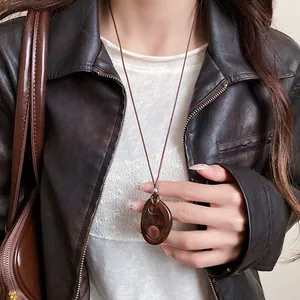 Gros plan d'un collier vintage en résine avec pendentif ovale évidé porté par un mannequin