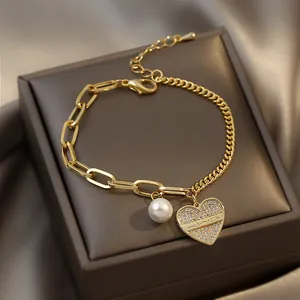 Elegant gold chain bracelet featuring a sparkling CZ heart charm and a white pearl drop