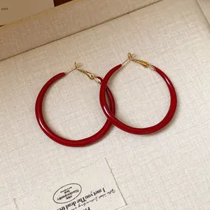 Macro detail of vintage Ankora red enamel hoop earrings with a high glossy finish