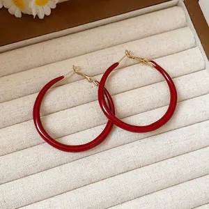 Detail view of vintage-style red enamel hoop earrings with gold-toned posts in a jewelry box