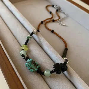 Detailed view of a Bohemian style necklace featuring turquoise beads and silver flower charm
