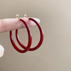 Close-up of elegant vintage burgundy red enamel hoop earrings with a glossy finish.