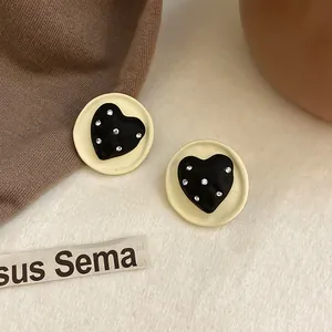 Primo piano di orecchini a forma di cuore con strass su uno sfondo minimalista.