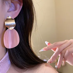 Close-up of pink acrylic and gold metal irregular oval earrings for women's jewelry