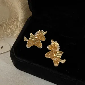 Close-up of gold-plated unicorn stud earrings with sparkling zircons on velvet box