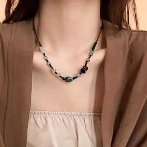 Detailed shot of a New Chinese style flower necklace with turquoise beads on a model.