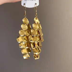 Close-up of gold irregular sequin tassel drop earrings with a metallic mirror finish