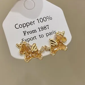 Detailed macro view of gold-plated unicorn earrings with shimmering yellow zircons.