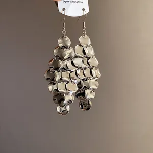 Close-up detail of silver irregular metal disc fringe earrings with leaf-like design