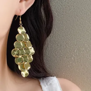 Gold-toned dangling earrings with layered geometric disks shown worn on a model