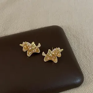 Close-up of gold plated unicorn stud earrings with sparkling amber zircon stones
