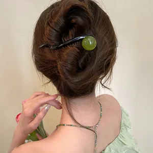Detailed view of an elegant green resin hair pin styled in an Asian bun hairstyle
