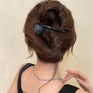 Minimalist black resin hair clip with a circular detail shown worn in a French twist