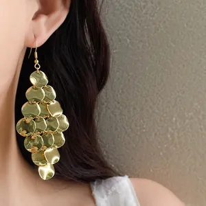 Close-up detail of gold multi-layered irregular disk tassel dangle earrings on model