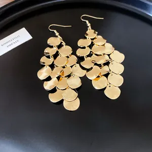 Detailed view of golden irregular leaf fringe earrings with minimalist metal scale charms