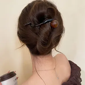 Detailed view of an elegant 8-shaped brown resin hair clip styled in a classic bun.
