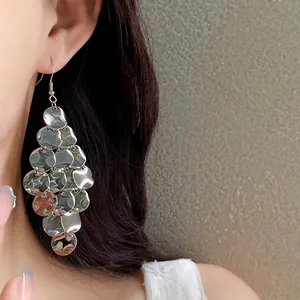 Close-up detail of stylish silver irregular metallic disc tassel earrings worn by a model