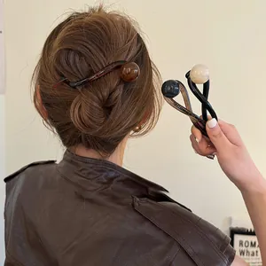Gros plan de pinces à cheveux rétro à perles portées en chignon et à la main