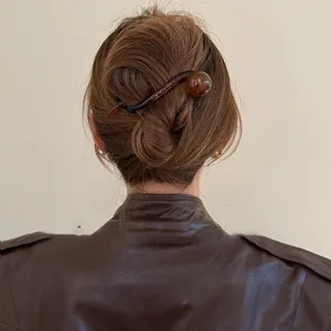 Gros plan détaillé d'une pince à cheveux rétro marron avec perle dans un chignon élégant
