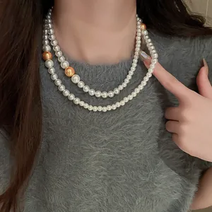 Detail view of a double-strand pearl necklace with elegant white and golden pearls.