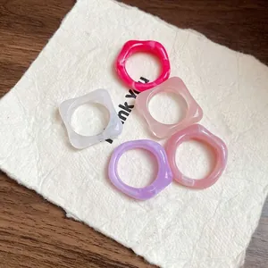 Assorted colorful chunky resin rings with marble patterns shown on a paper background