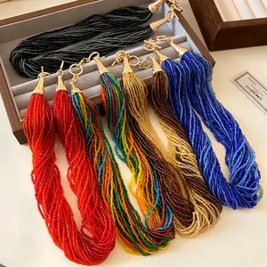 Close-up of multi-layer colorful rice bead necklaces with gold clasps in a jewelry tray.