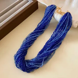 Macro detail of a vintage multi-strand blue seed bead necklace featuring a golden toggle clasp