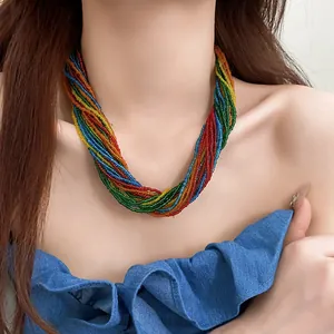 Close-up view of a vibrant multi-strand rainbow seed bead necklace worn by a model.