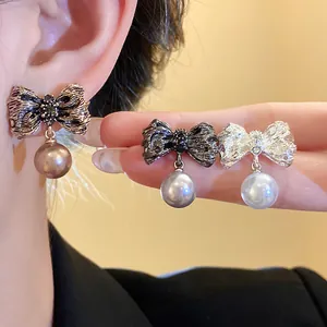 Detail view of retro pleated bow earrings with pearl drops in various metallic finishes