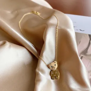 Close-up of a gold-plated titanium steel necklace featuring a cute bear pendant on satin fabric